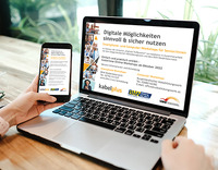 Ein Laptop steht auf dem Tisch, eine Hand hält ein Handy daneben. Auf den Displays ist Information zum Smartphonekurs zu sehen.