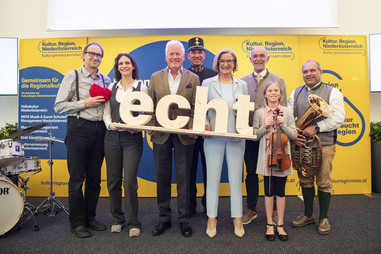 Eine Gruppe von Ehrenamtlichen aus unterschiedlichen Kultur- und Bildungsvereinen hält die Holzbuchstaben "echt" mit der Landeshauptfrau in die Kamera. 