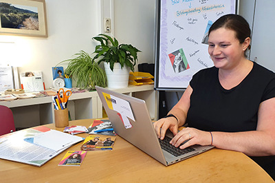 Bildungsberaterin Christa Sieder sitzt am Schreibtisch und schreibt am Laptop.
