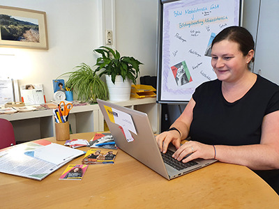 Bildungsberaterin Christa Sieder sitzt am Schreibtisch und schreibt am Laptop.