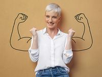 Frau steht vor einem braunen Hintergrund. Auf diesem sind von ihrer Schulter weg, Arme gezeichnet die die Muskeln anspannen, wie ein Bodybuilder. Das Foto soll Motivation und innere Stärke symbolisieren.
