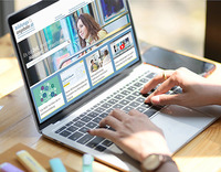 Aufgeklappter Laptop, auf dem Bildschirm sieht man die Startseite der Website "Bildungsangebote.at". Zwei Frauenhände tippen auf der Tastatur.