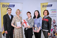 Gruppenbild mit einem Mann und fümf Frauen. Die Gewinnerin des Wettbewerbs steht in der Mitte und hält das Peket mit ihrem Gewinn in der Hand.