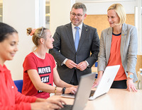 Zwei junge Frauen sitzen am Laptop, Landesrat Schleritzko und BhW Geschäftsführerin Therese Reinel stehen daneben und unterhalten sich mit einer der beiden Damen.