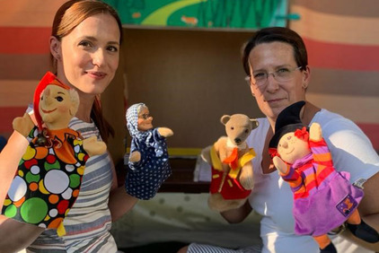 Zwei Damen haben Handpuppen an den Händen und lachen in die Kamera. Kasperltheater im BhW Paasdorf.