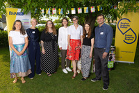 Auf dem Foto stehen sieben Personen lächelnd nebeneinander im Freien, zwischen zwei Roll-Ups mit den Logos von BhW Bildung hat Wert und Kulturregion Niederösterreich. Im Hintergrund hängt eine bunte Wimpelkette, und die Gruppe wirkt freundlich und professionell.