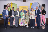 Gruppenbild mit den erwähnten Personen. Im Hintergrund große bunte Würfel mit BhW-Projektinfos und ein Roll der Kulturregion.