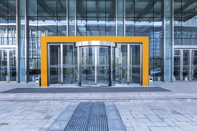 Ein Eingang in ein großes Gebäude. Dieser ist mit einer gut sichtbar orangen Markierung zu erkennen.