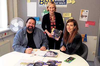 Gruppenbild mit Jakob Sint, Therese Reinel und Birgit Schierhuber. Sie sitzen an einem Tisch auf dem einige Exemplare der Barrierefrei-Broschüren liegen.