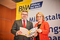 Landesrat Ludwig Schleritzko und BHW-Landesvorsitzende Bettina Rausch stehen vor einem BhW-Rollup und halten gemeinsam eine bhW-Broschüre in den Händen.