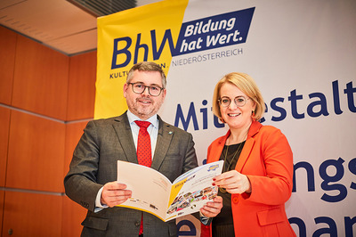 Landesrat Ludwig Schleritzko und BHW-Landesvorsitzende Bettina Rausch stehen vor einem BhW-Rollup und halten gemeinsam eine bhW-Broschüre in den Händen.