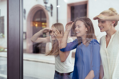 Drei junge Damen stehen vor einem Schaufenster und blicken hinein. Was es dort zu sehen gibt ist nicht im Bild.