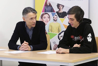 Lernbegleiter Michael und Teilnehmer Matthias sitzen an einem Tisch und schauen auf Lernunterlagen.