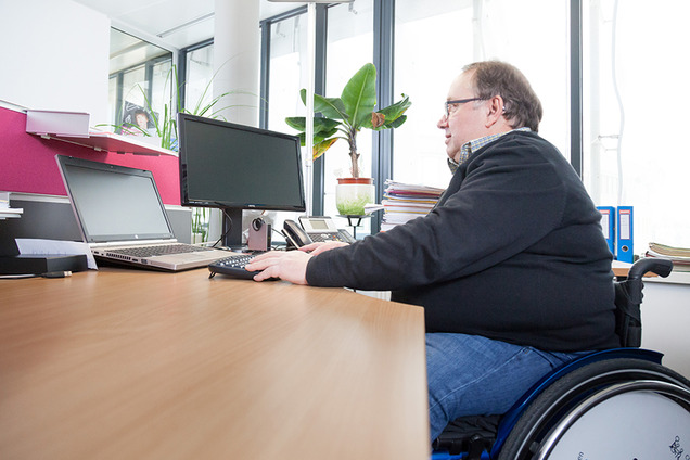 Ein Mann im Rollstuhl arbeitet an einem Computer.
