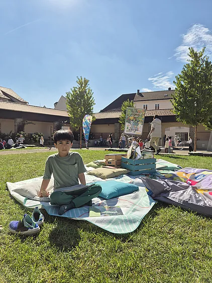 Ein Bub sitzt auf einer Picknickdecke mit einem Buch im Schoß