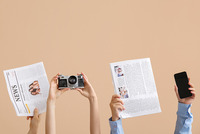 Das Bild zeigt einige hochgestreckte Arme, die Zeitungen, eine Kamera und ein Smartphone halten.