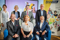 Die Hauptpersonen von Talk im Turm stehen auf einem Gruppenbild. 4 Personen stehen, drei sitzen auf einer blauen Couch. 