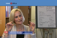 BhW Geschäftsführerin Therese Reinel sitzt in einem Schulungsraum vor einem Bücherregal und Flipchart und wird interviewt.