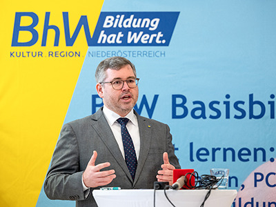 Ludwig Schleitzko, Landesrat steht vor einem Werbeplakat der Basisbildung und hält eine Rede.