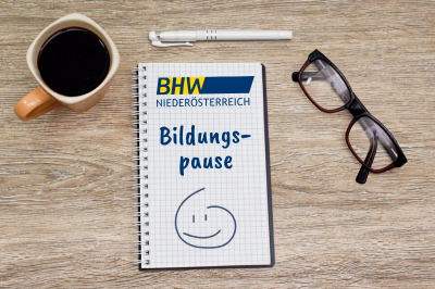 Das Bild zeigt einen Schreibtisch von oben. Darauf liegen ein Block und eine Brille, daneben steht eine Kaffeetasse.