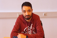 Ein Mann sitzt wissbegierig an einem Tisch. Vor ihm liegen seine Lernunterlagen. 