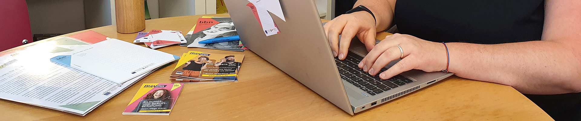 Bildungsberaterin Christa Sieder sitzt bei einem Tisch und tippt in ihren Laptop. Sie berät, nicht nur vor Ort, sondern auch online ratsuchende Personen.