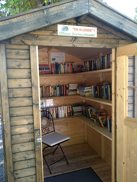 kleines Holzhaus mit Regalen voller Bücher zum Tauschen.