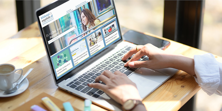 Aufgeklappter Laptop. Auf dem Bildschirm sieht man die Startseite der Homepage bildungsangebote.at. Hände einer Frau tippen auf der Tatstatur.
